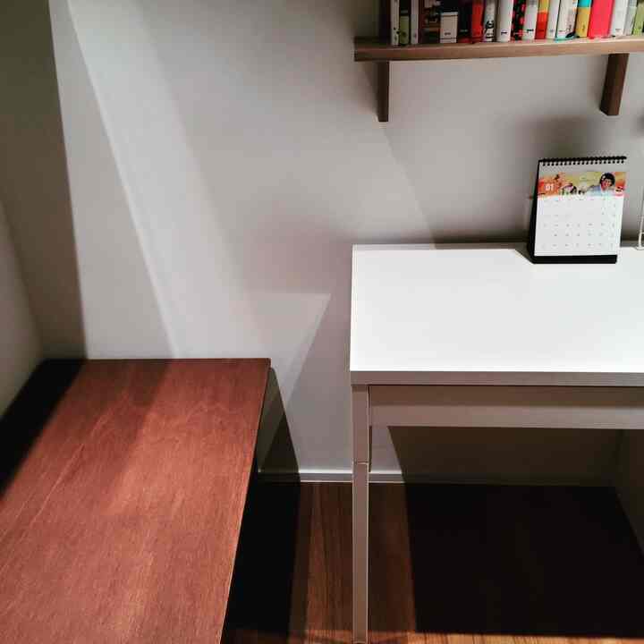 Natural-toned small room with white walls, wooden storage bench, and white desk furniture