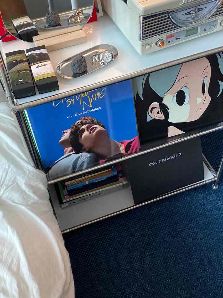 ネイビーカーペットの床とメタル製の棚にレトロなLPターンテーブルと様々なLPが置かれた音楽鑑賞スペース