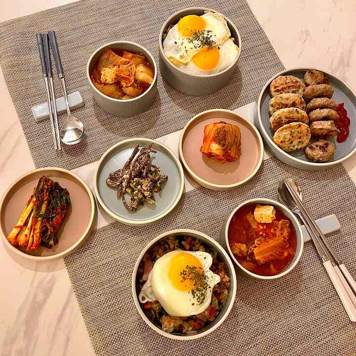 Warm brown and ivory toned dining space featuring various Korean-style bowls and plates neatly arranged creating cozy meal atmosphere