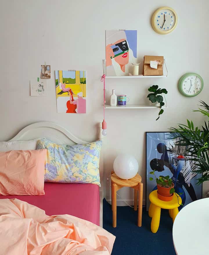 Natural toned bedroom with white walls, wood stools, and pink bedding creating a cozy atmosphere