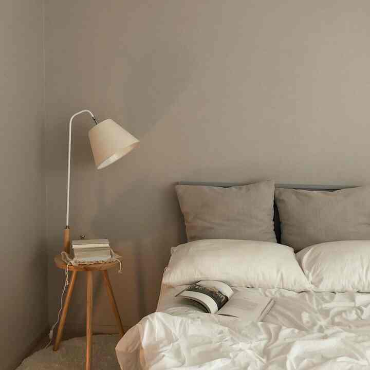 Natural-toned bedroom featuring a beige table lamp and white bedding with a cozy ambiance