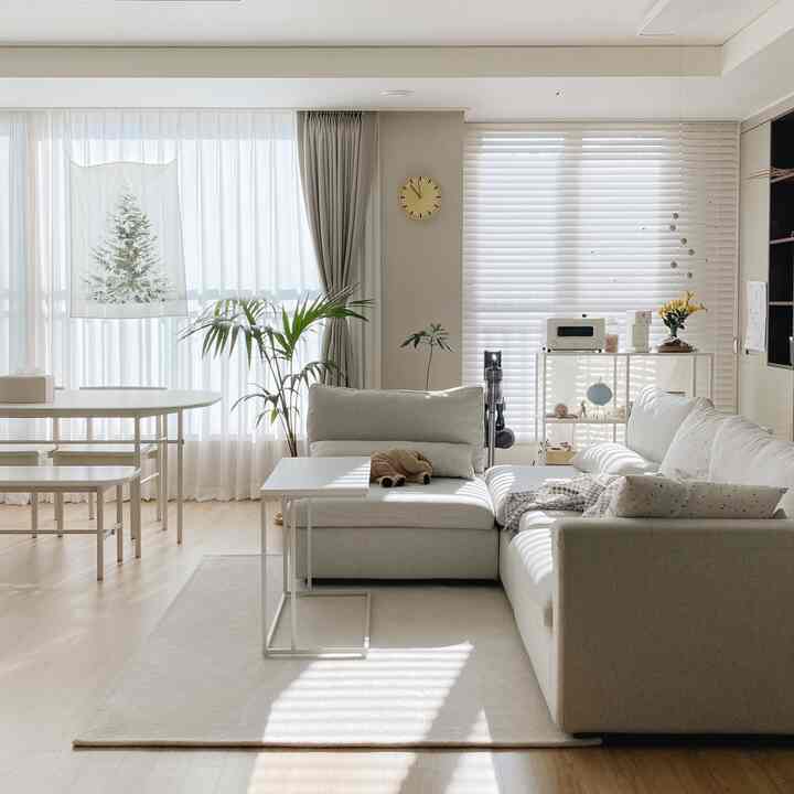 Bright living room in white and natural tones featuring sectional sofa and dining table with a simple, airy atmosphere