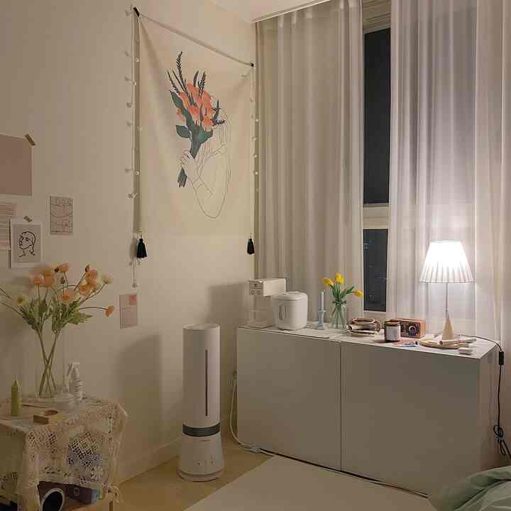 柔らかなナチュラルトーンの寝室、白いキャビネット上に加湿器とテーブルランプが配置された雰囲気のあるインテリア。