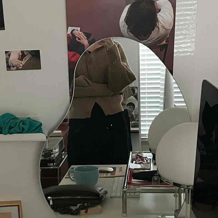 White and black toned home office space featuring an irregular shaped mirror and desk lamp, compact and functional workspace