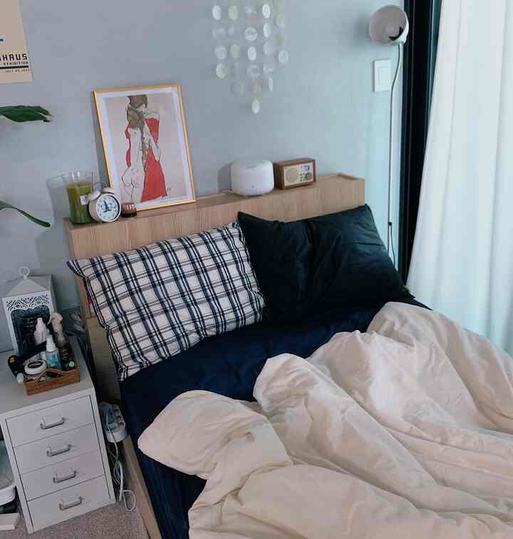 ネイビーとホワイトのトーンのワンルーム寝室、ネイビーのベッドとホワイトの掛け布団カバーが配置された落ち着いた雰囲気のインテリア