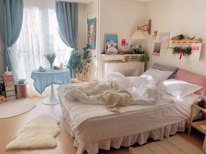 ホワイトとスカイブルーのトーンの寝室、枕と寝具が整えられたホテルライクな雰囲気のインテリア