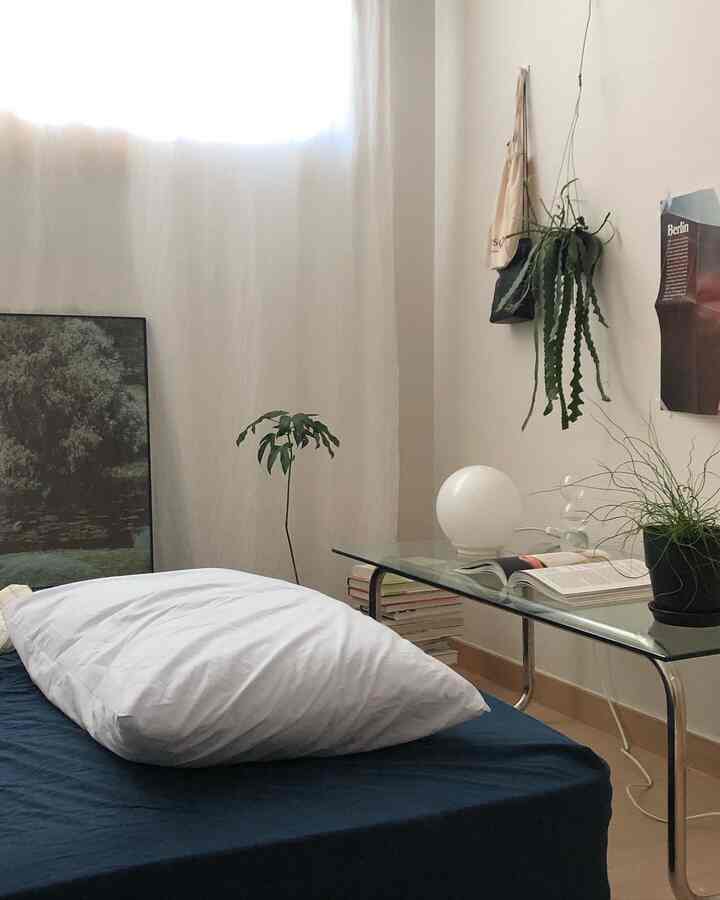White and navy toned bedroom featuring a navy bed with white pillow and transparent side table in a natural modern style
