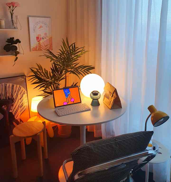 White and light brown toned home office featuring a round table, lamps, and plants creating a warm atmosphere
