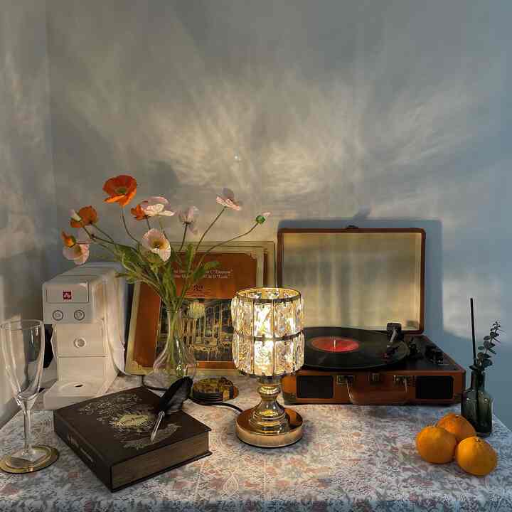 Cozy retro home cafe space with white walls featuring an antique table lamp, brown turntable, poppy flowers in vase, and coffee machine