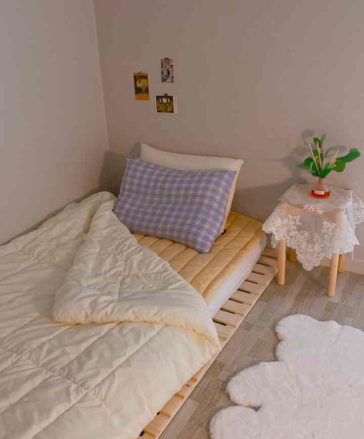 Natural-toned compact bedroom featuring wooden nightstand and bear-shaped rug in a modest single household room