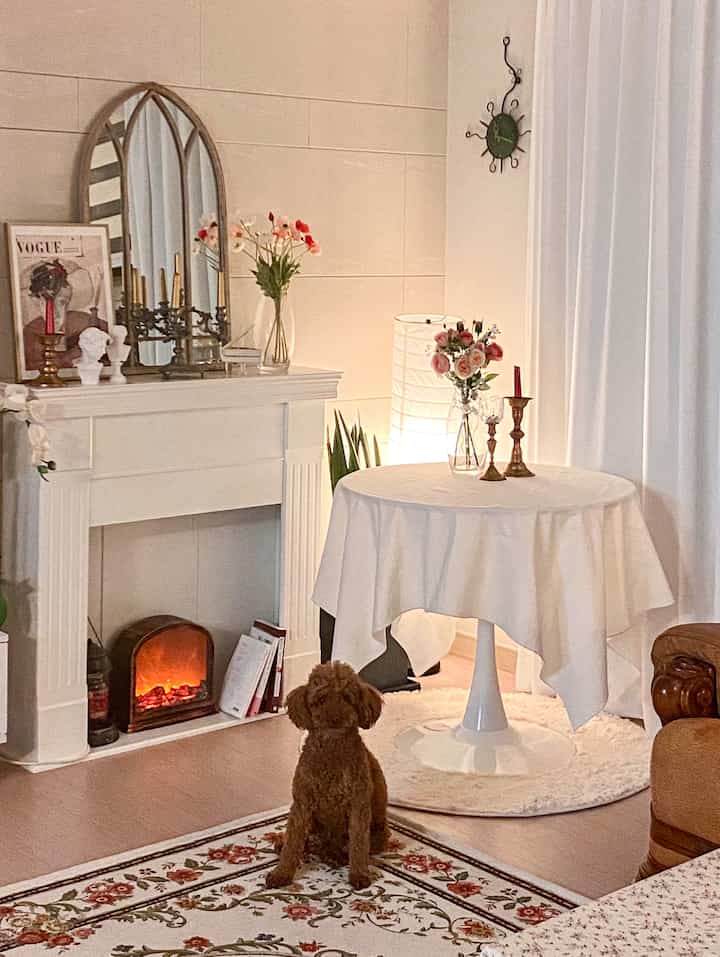 Ivory and beige toned living room featuring an antique fireplace, French-style arched mirror, and white table with flowers and candles in a harmonious setting