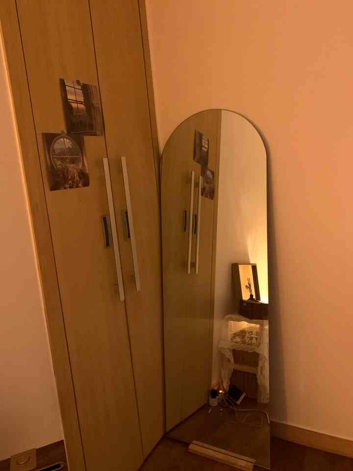 Narrow space in beige and natural tones featuring a closet and an arch-shaped full-length mirror, creating a warm atmosphere