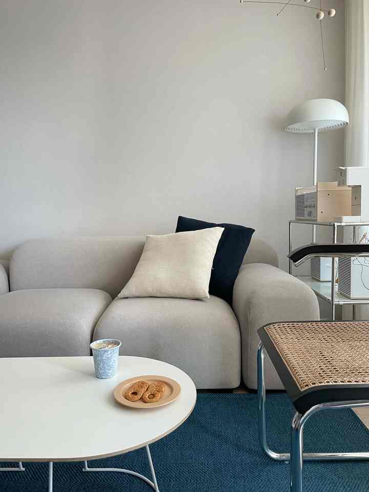 White and blue toned living room featuring beige sofa with cushions and white round coffee table in a simple modern style space