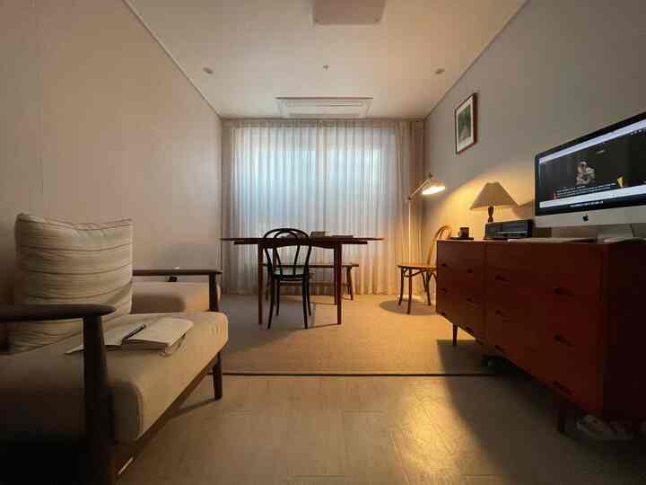 Natural-toned living room with warm brown and beige hues, featuring an extendable dining table and a computer workstation creating a cozy atmosphere