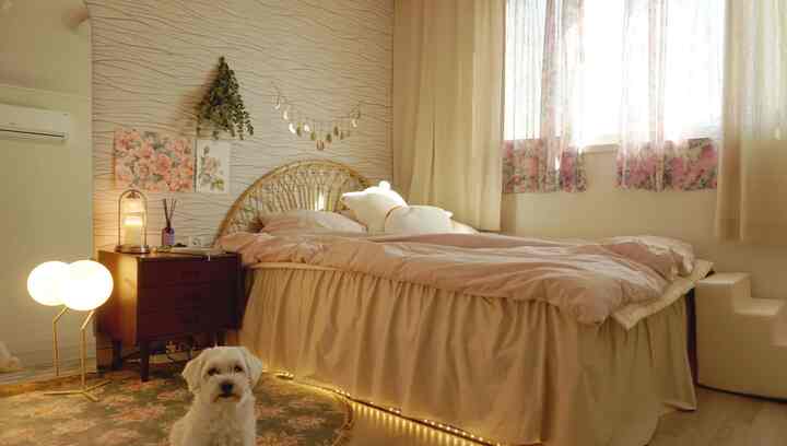Warm beige toned bedroom featuring a rattan bed, floral curtains, a dog, and bedside lighting creating a cozy romantic atmosphere