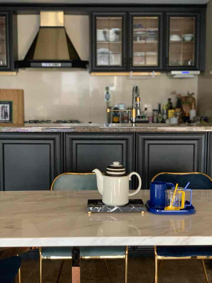 ブラックとゴールドを基調としたモダンなキッチン、大理石のダイニングテーブルとゴールドの椅子が配置された印象的なインテリア