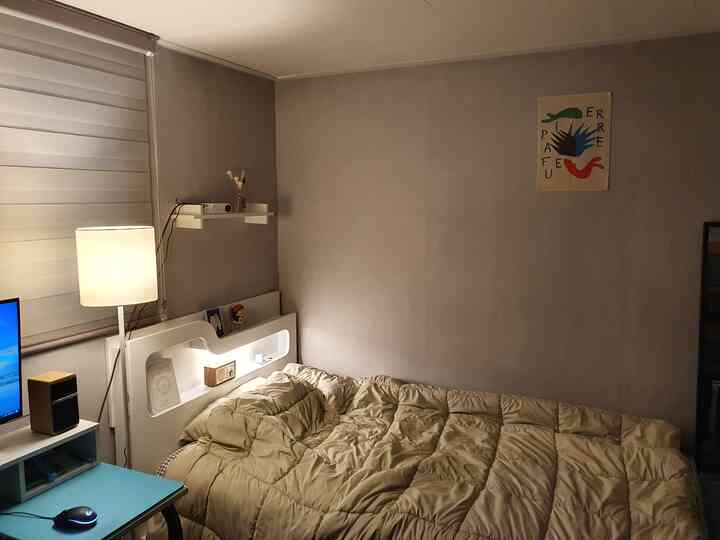 ナチュラルな色調の寝室、ベージュの寝具とフロアランプ、デスクが配置された雰囲気のある空間