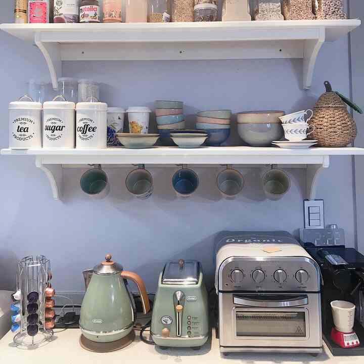 White walls and natural tone wall shelves in a kitchen, vintage-style electric kettle and toaster create a cozy home cafe atmosphere