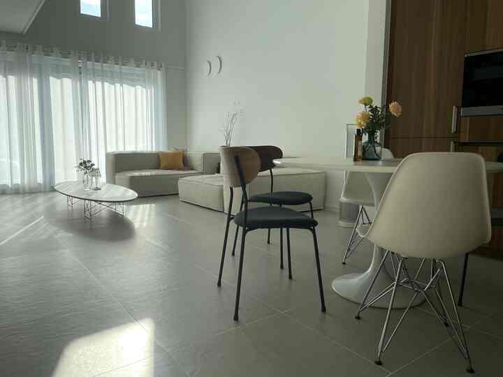 Natural color and white toned living and dining room featuring beige sofa and dining chairs in a modern setting