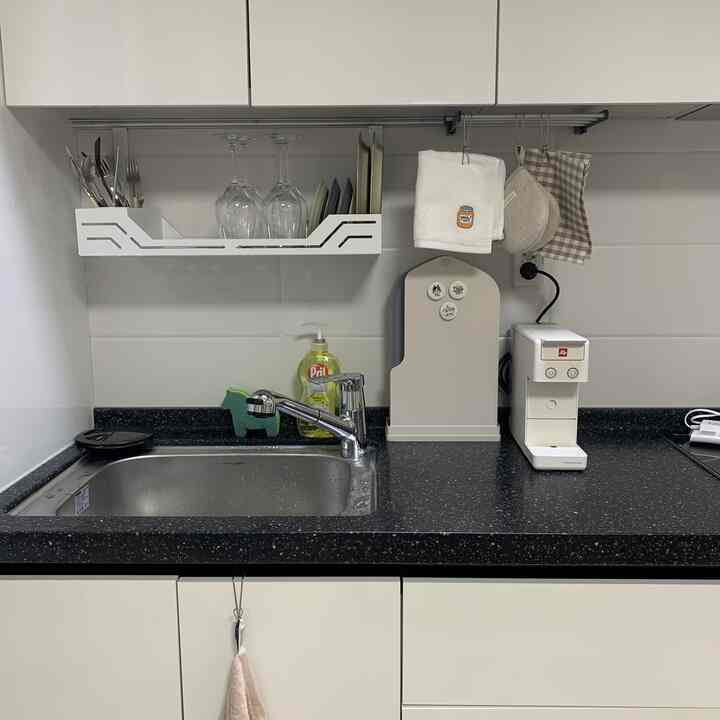 白と黒の落ち着いた色調のキッチン、シンクとコーヒーマシン、整理されたキッチン用品が配置された印象的な空間