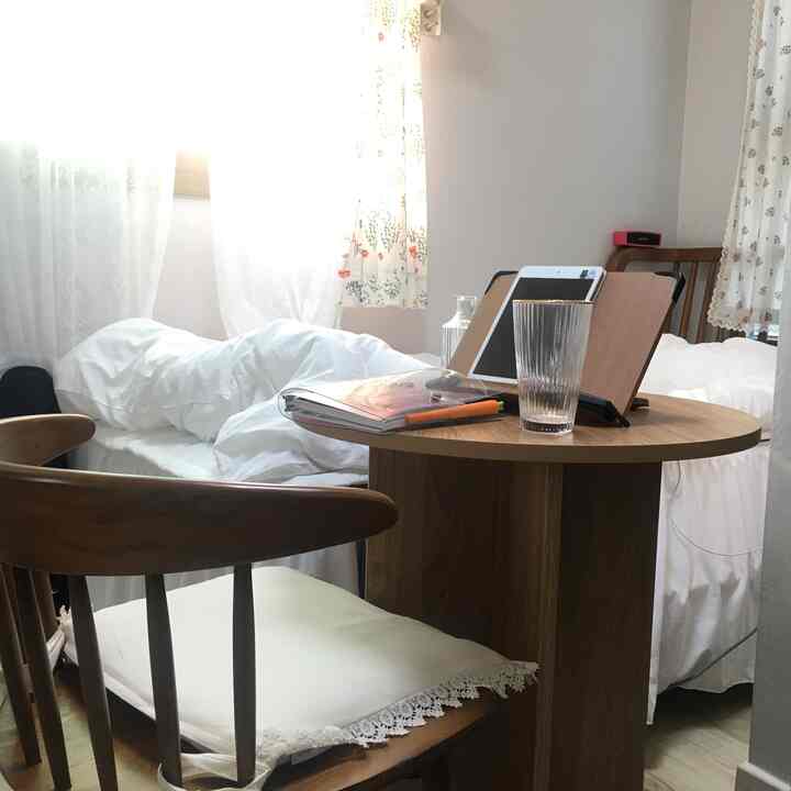 A cozy bedroom with white bedding, wood-tone dining table and chairs, and romantic curtains for two-person use