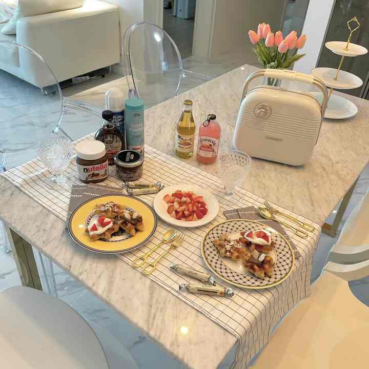 白とゴールドのアクセントが映える大理石のダイニングテーブルにホームカフェスタイルのワッフルと食器が配置されたシンプルモダンダイニング