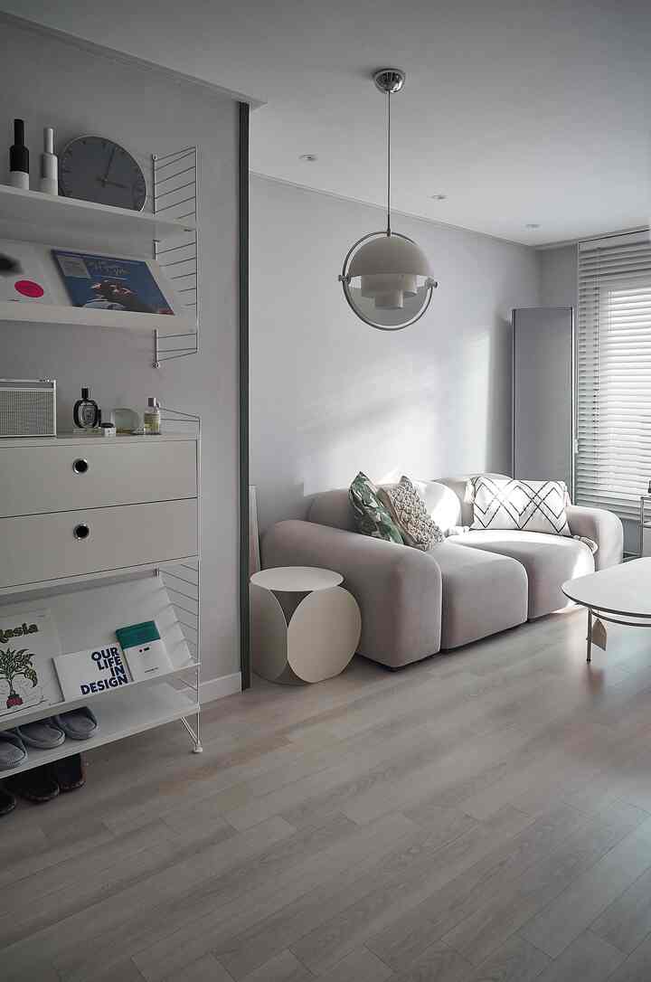 White and gray toned round living room featuring curved sofa and pendant light with a sophisticated atmosphere