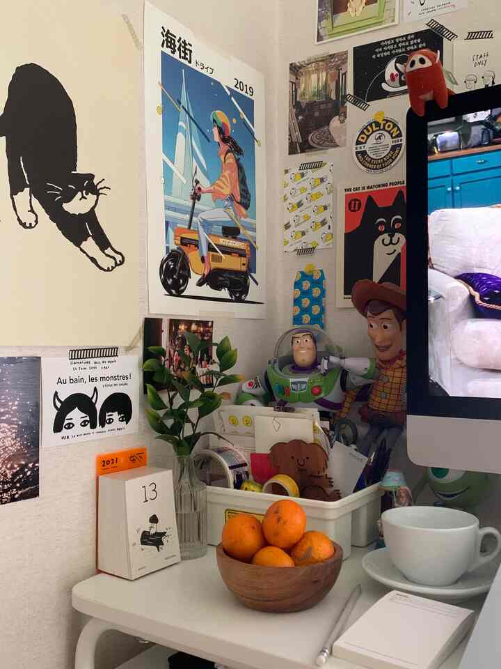 白とナチュラルトーンのホームオフィス空間、ポスターと植物が配置された整ったデスク上のかわいらしい小物たち