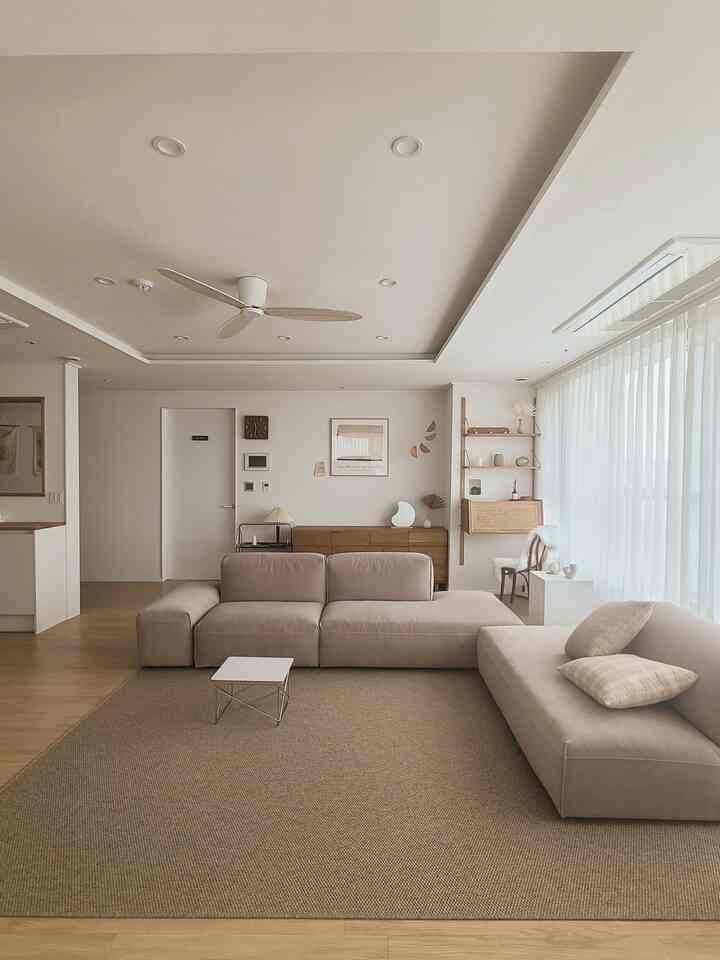 Natural toned living room featuring large sofas and white curtains with a clean and cozy atmosphere