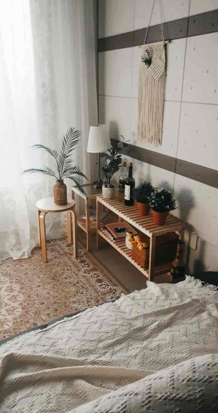 ナチュラルな色調のリビング、木製の棚と丸椅子、白いカーテンとカーペットが居心地の良い空間を演出する