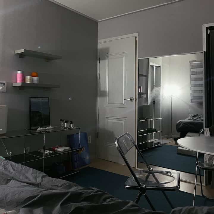 Charcoal and transparent materials in a modern bedroom, with a large full-length mirror and rug creating a cozy space