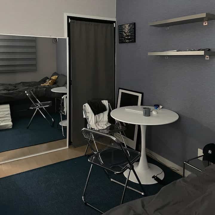 Blue-toned bedroom featuring a round table, rug, and mirror with a simple cozy atmosphere