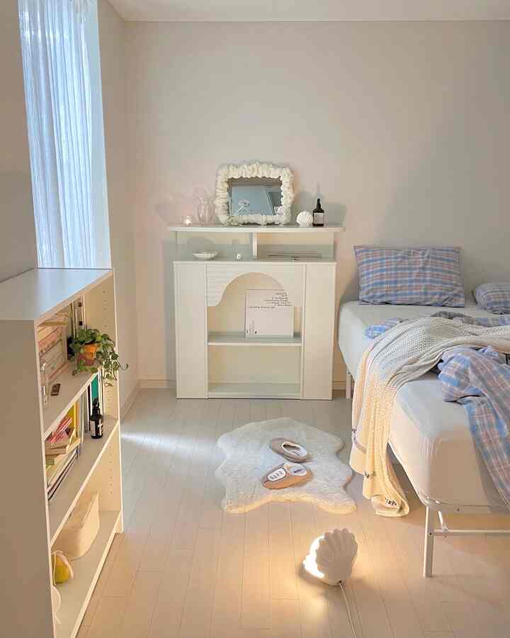 Bright white-toned bedroom featuring a simple modern bookshelf and fireplace console in a serene setting