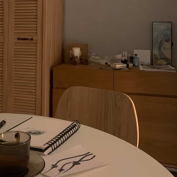 Cozy dining room with natural wood tones and warm beige hues, featuring a round table, sideboard, and closet