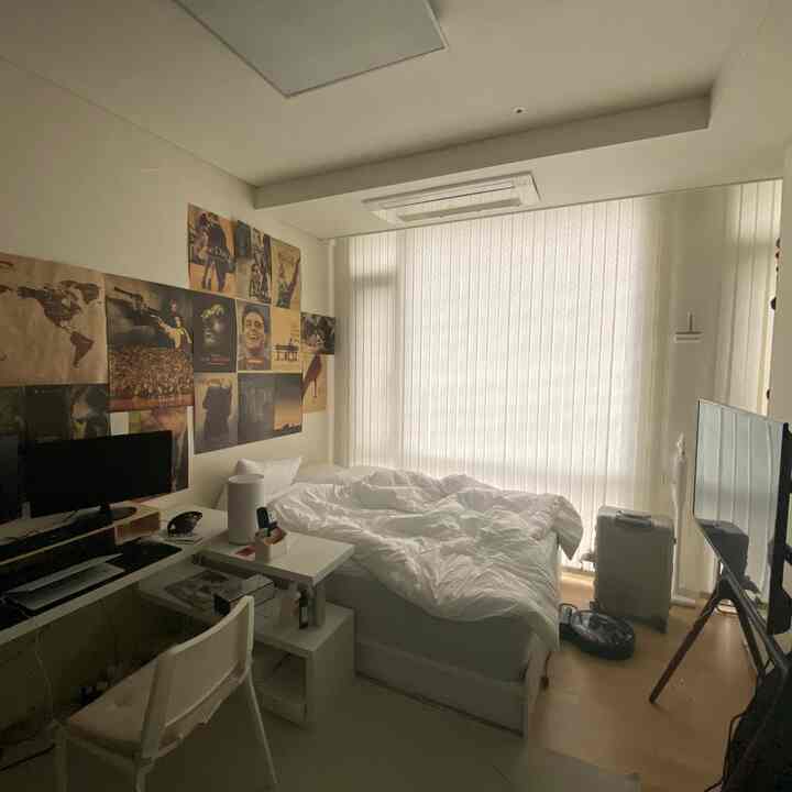 White-toned studio bedroom with home office featuring bed and computer desk, creating a cozy atmosphere