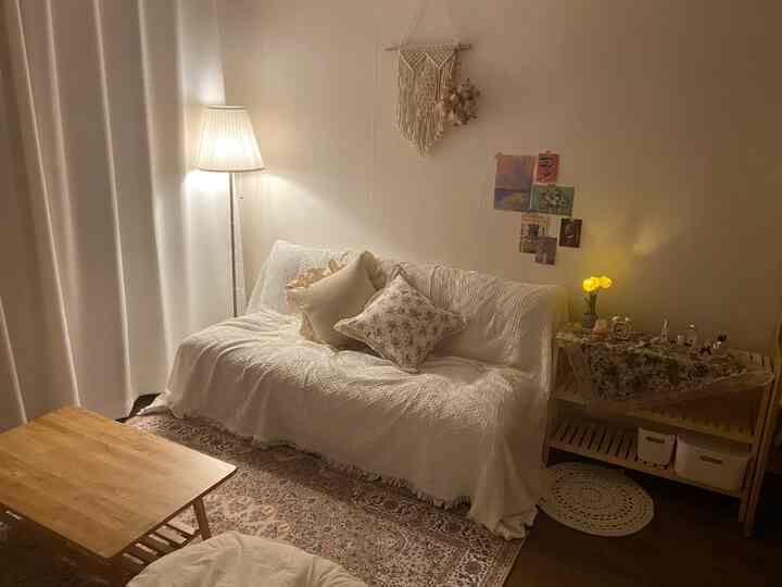 Cozy living room with warm white tones and vintage sofa, featuring a floor lamp and rug creating a comforting atmosphere