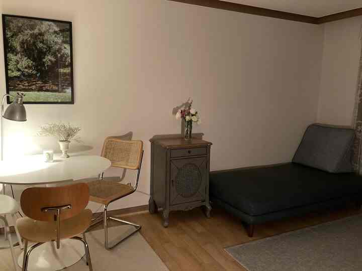 ナチュラルな色調のリビング、丸いダイニングテーブルとソファ、照明が配置された雰囲気のある空間