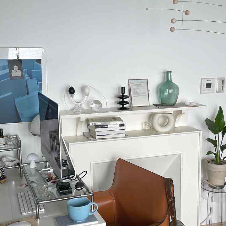 White and brown toned home office space featuring a glass desk and leather armchair in a sleek Nordic style interior