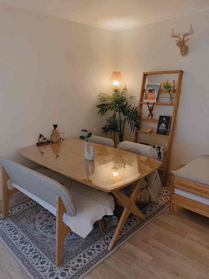 ナチュラルカラーのダイニングルーム、木製テーブルとベンチ、ラグ、フロアランプが配置された温かみのある印象的な空間