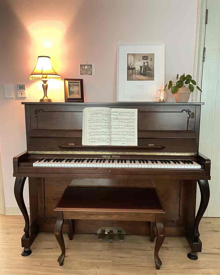 ナチュラルな木目調とヴィンテージ風の子供部屋、ピアノと額縁、温かみのある照明が配された雰囲気のあるインテリア