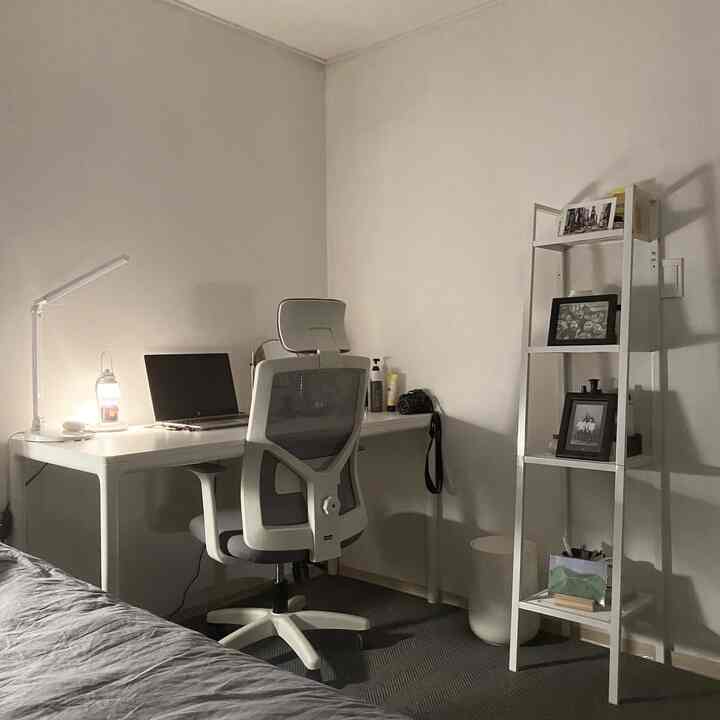 白とグレーのトーンのホームオフィス、シンプルモダンなインテリアに配置された机とオフィスチェア、棚が特徴的な印象的な空間