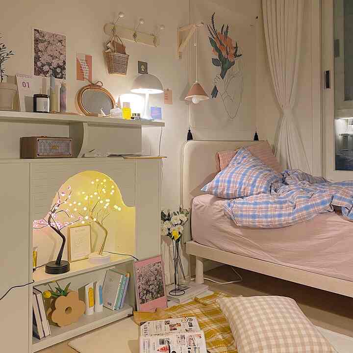 Beige and white toned studio bedroom featuring pillows, bedding, and warm lighting creating a cozy atmosphere