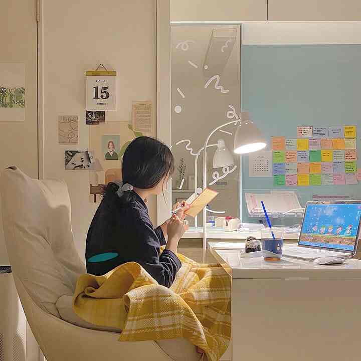 ナチュラルなベージュの壁とホワイトのデスクがある一人用のホームオフィス、黄色のブランケットがかかったクッションチェアとスタンドライトが温かみのある雰囲気を演出