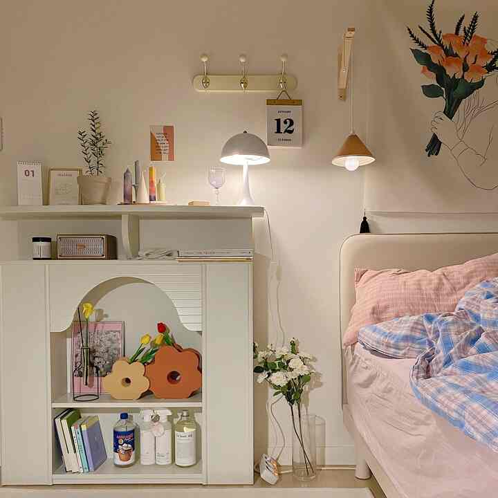 ホワイトとピンクの色調の寝室、ベッドと棚、花瓶が配置された雰囲気のあるインテリア