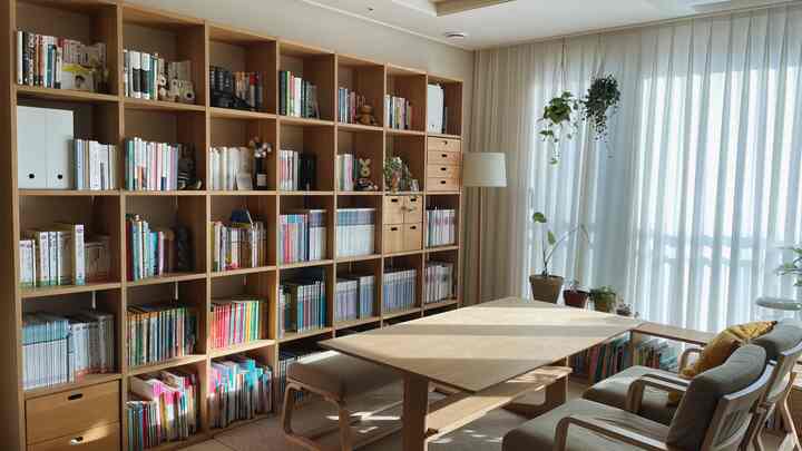 木目調が特徴のリビングダイニング、広い本棚とダイニングテーブルが配置された自然なプランテリア空間