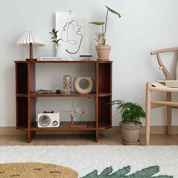 白い壁と木製の棚、自然の植物とワイチェアが配置されたミニマルなインテリア空間