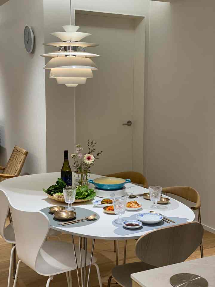 White and natural toned dining room featuring a large dining table with chairs and a pendant light illuminating the space