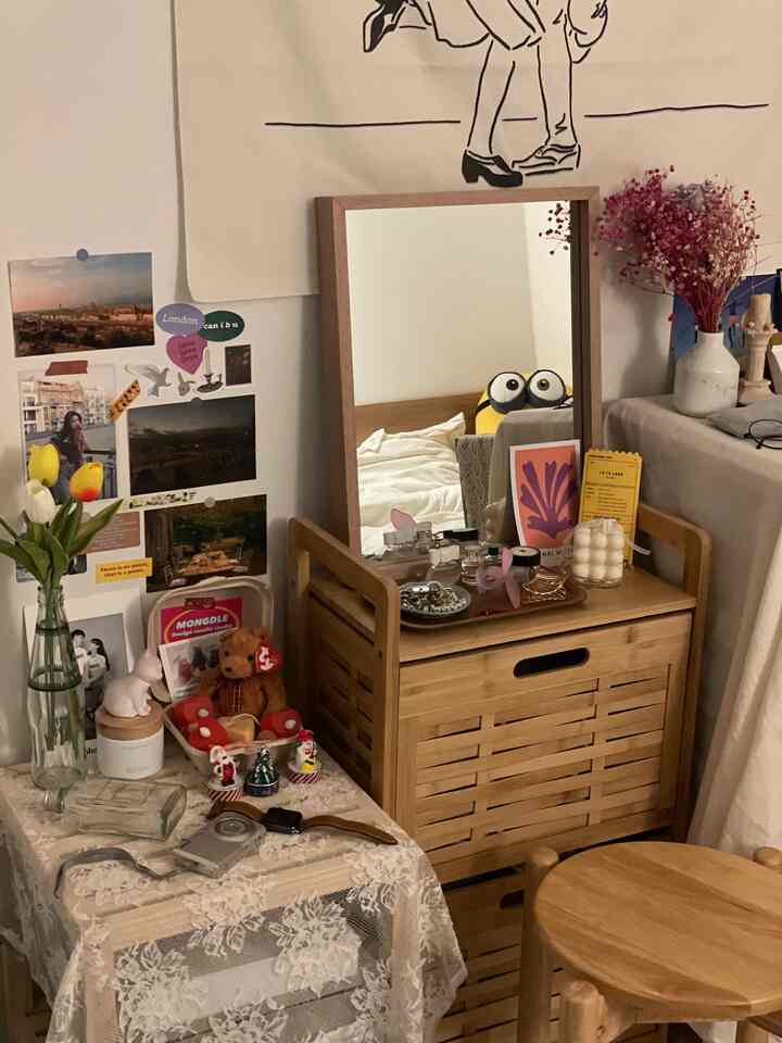Beige-toned small room featuring wood tone two-tier storage cabinet with mirror, flowers and decor creating cozy ambiance