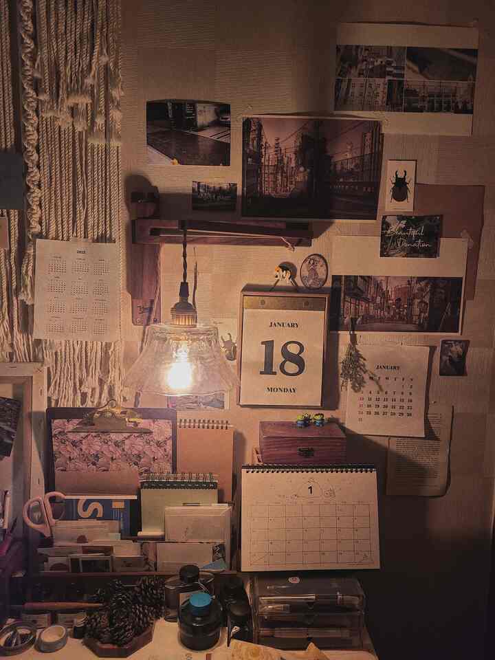 Warm brown-toned study space featuring multiple calendars and a glowing pendant light creating a cozy desk ambiance