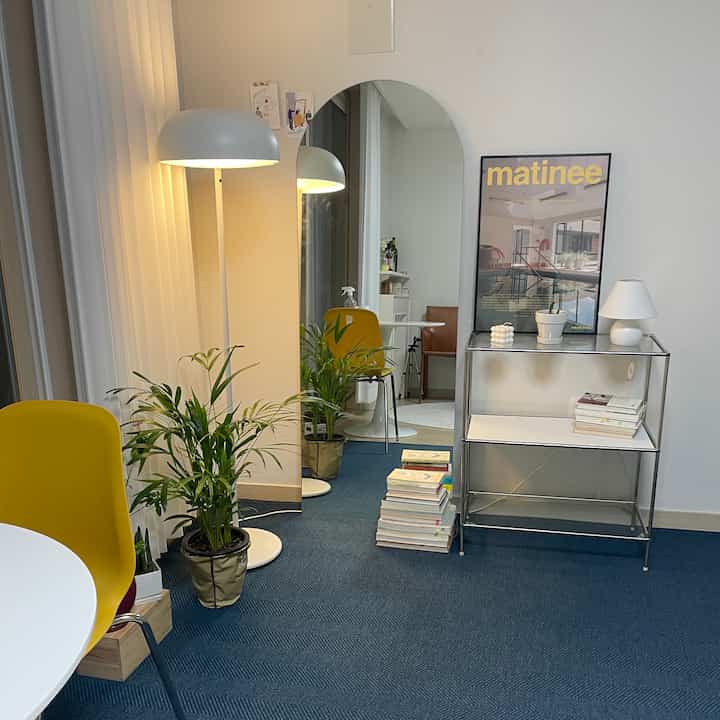 A simple modern dining room in white and blue tones, featuring yellow chair, floor lamp, and large arch mirror harmoniously arranged